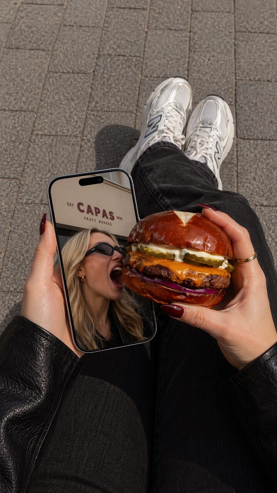 Guest holding a Capas smash burger outside the storefront
